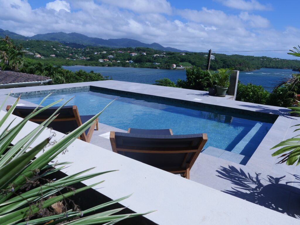 a pool with chairs and a view of the ocean